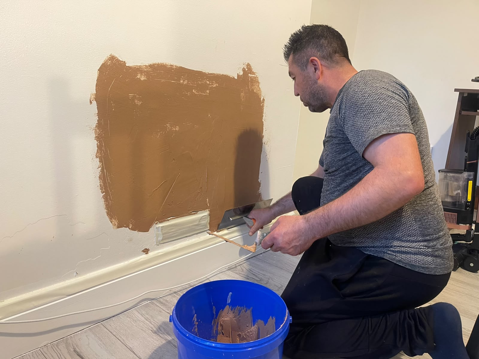 Ceylin decorator carefully smoothing plaster on an interior wall